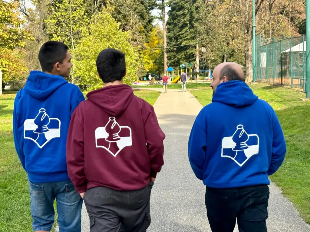 Personas del Club Ajedrez Diagonal caminando juntas por un parque con sudaderas del club